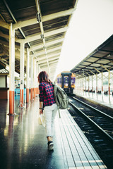 Young hipster woman waiting on the station platform with backpack. Travel concept.
