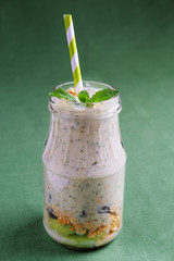 Smoothie bottles with granola, kiwi, nuts, yoghurt and mint