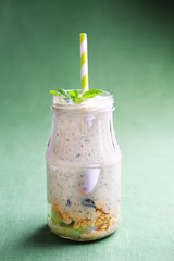 Smoothie bottles with granola, kiwi, nuts, yoghurt and mint