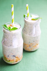 Smoothie bottles with granola, kiwi, nuts, yoghurt and mint