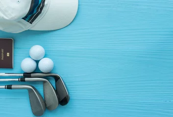 Poster Golf clubs, golf balls, cap, passport on blue wooden table, with copy space. © BoonritP
