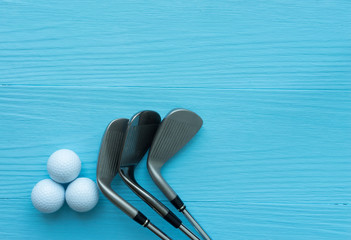 Golf clubs, golf balls on blue wooden table, with copy space.
