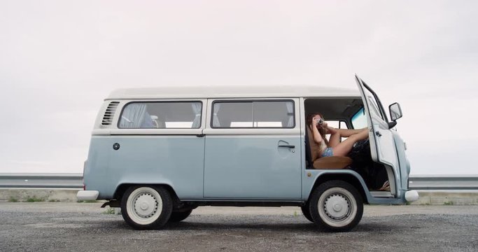 Portrait Beautiful hippie girl taking photos with retro digital camera road trip camper van