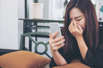 Fototapeta premium A beautiful asian woman looking at smart phone with feeling sad and cry in cafe