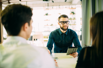 Obraz premium Cheerful young couple bonding to each other and smiling while looking at some man sitting in front of them and gesturing