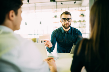 Obraz premium Cheerful young couple bonding to each other and smiling while looking at some man sitting in front of them and gesturing