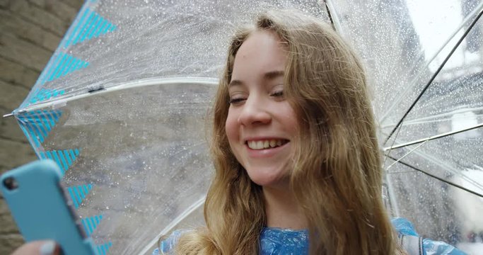 Tourist woman taking selfie using smartphone in Barcelona on Vacation in rainy weather enjoying European summer holiday travel adventure