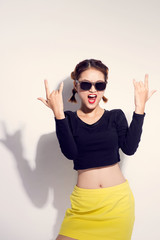 Young asian girl doing emotion. Dressed in a black shirt and yellow skirt. Warm color. White background, not isolated