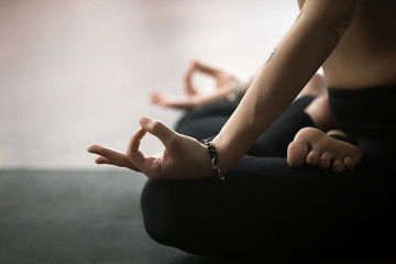 Young yogi woman practicing yoga concept, sitting in Padmasana exercise in studio or at home, Lotus...