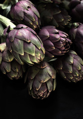 Ingredients. Fresh textured artichokes on a dark backgroun