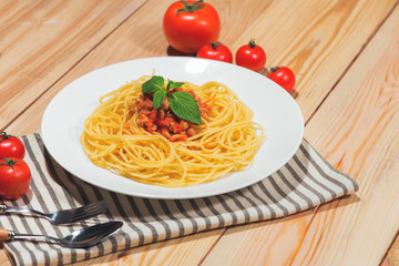 Plate of tasty spaghetti with tomato sauce and meat on wooden table.
