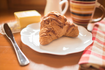 Breakfast. Croissant with cheese, butter, coffee with milk.