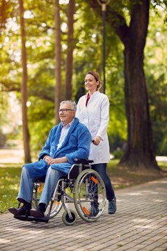 elderly man on wheelchair with nurse outdoor.