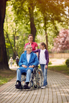 Disabled man in park spending time together with his daughter and granddaughter.