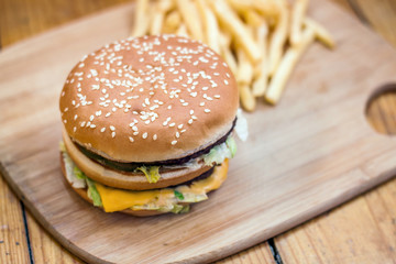 Fast food set big hamburger and french fries on wood background