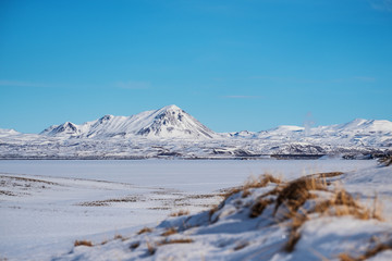 Winter Landscape, sow field with frozen lake and snow mountain with clear blue sky