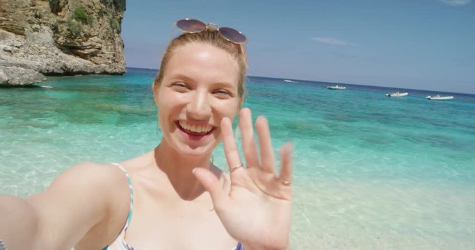 Beautiful woman having video chat using smartphone on beach taking selfie photograph smiling enjoying tropical nature background view on  summer vacation travel adventure POV