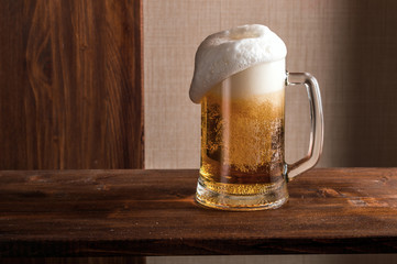 half-empty glass of beer on background wooden table