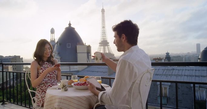 Young tourist couple in Paris hotel enjoying breakfast on terrace view of Eiffel Tower at Sunrise in the morning