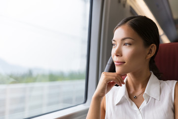 Asian woman traveler contemplating outdoor view from window of train. Young lady on commute travel...