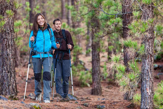 Multiracial Group Of Hikers In Forest. Couple Hiking In Autumn In Nature Outdoors. Asian Woman Hiker In Front Smiling Happy, Man Walking Behind.