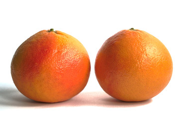 Two red grapefruits on a white background
