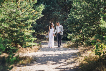 Obraz premium Beautiful newlyweds couple walking in the woods. Honeymooners.