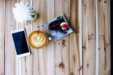 latte art coffee with bekery and smartphone or tablet on wood table.