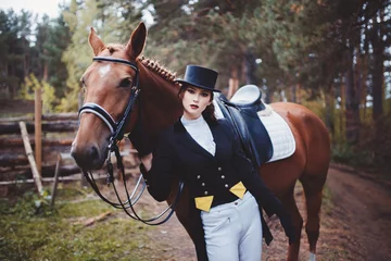 Foto op Canvas Portrait Jockey girl next to a horse, riding, concept of advertising an equestrian club, preparing for jumps. Summer. Toning. © Parilov