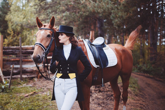 Portrait, riding, concept of advertising equestrian club caring for a horse. Jockey girl next to the horse. Corrects the bridle. Summer. Toning.