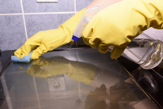 Scrubbing The Stove And Oven With Yellow Gloves