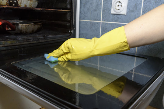 Scrubbing The Stove And Oven With Yellow Gloves