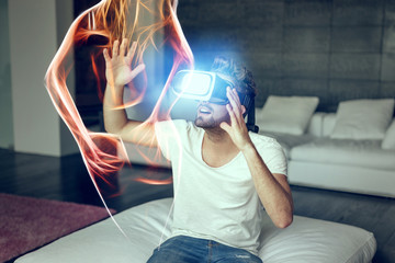Young man with VR headset playing with fiery virtual sexy woman silhouette
