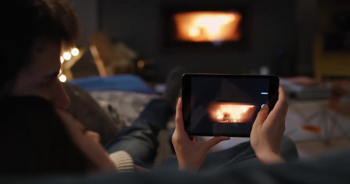 Closeup of couple using digital tablet by fireplace taking photos fire social media sharing on digital device
