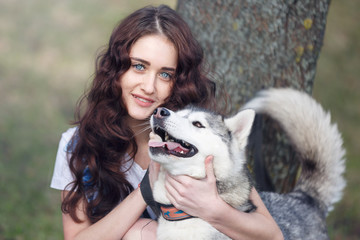 Teenage girl is hugging the husky dog outdoors