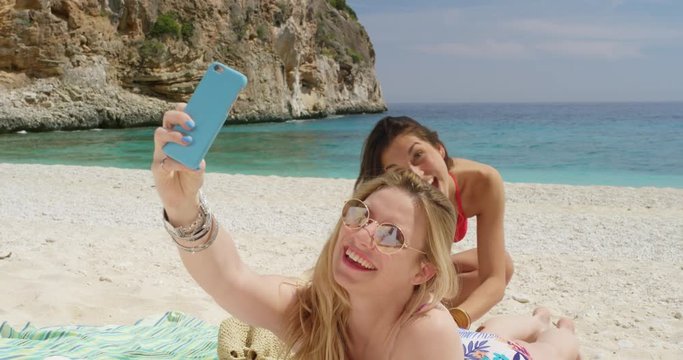 Girl friends putting on suncreen taking selfie photograph with smartphone woman enjoying tropical beach nature background view on  summer vacation travel adventure