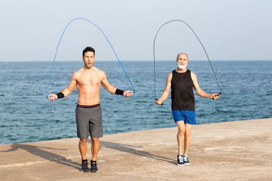 Senior macht Seilchenspringen mit Trainer am Meer