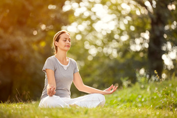 Female relaxing in yoga pose in green nature