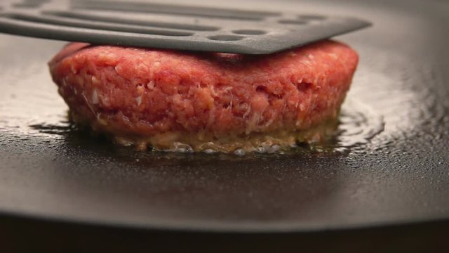 Raw burger is cooking on a stone grill