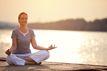 Fototapeta na wymiar Woman on dock sitting in yoga pose