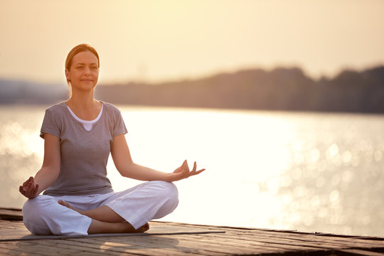 Woman On Dock Sitting In Yoga Pose