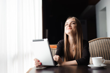 Beautiful pregnant woman using digital tablet at table in cafe