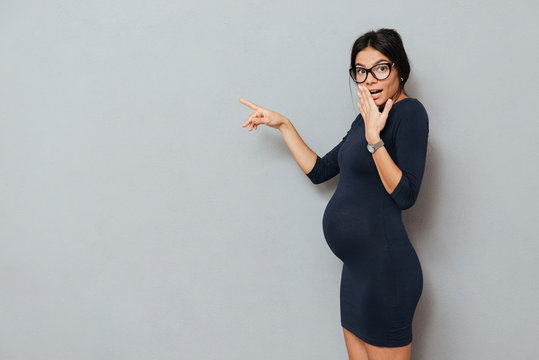 Surprised pregnant business lady pointing.
