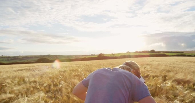 Rear view Man wearing virtual reality headset standing in golden wheat field watching 360 video immersive concept at sunset
