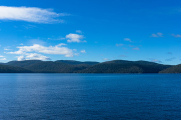 Naklejka na ściany i meble Ocean landscape with forest mountains in the distance