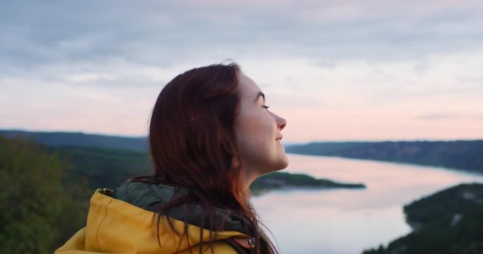 Close up of beautiful young woman looking up at sky out towards horizon view on top of mountain enjoying mindfulness spiritual moment in nature