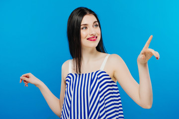 Laughing beautiful emotional curly hair style woman looking up with hand near the face on bright blue background