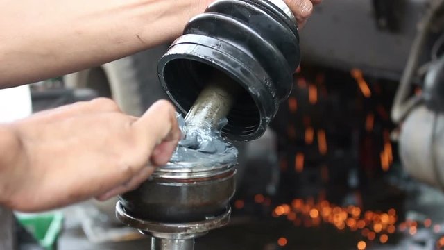 mechanic doing maintenance applying grease to shaft