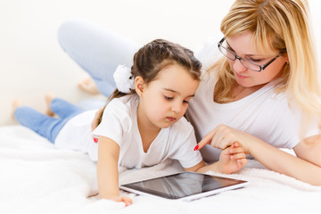 mother and baby are looking to play and read tablet computer on the couch at home