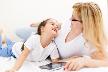 mother and baby are looking to play and read tablet computer on the couch at home